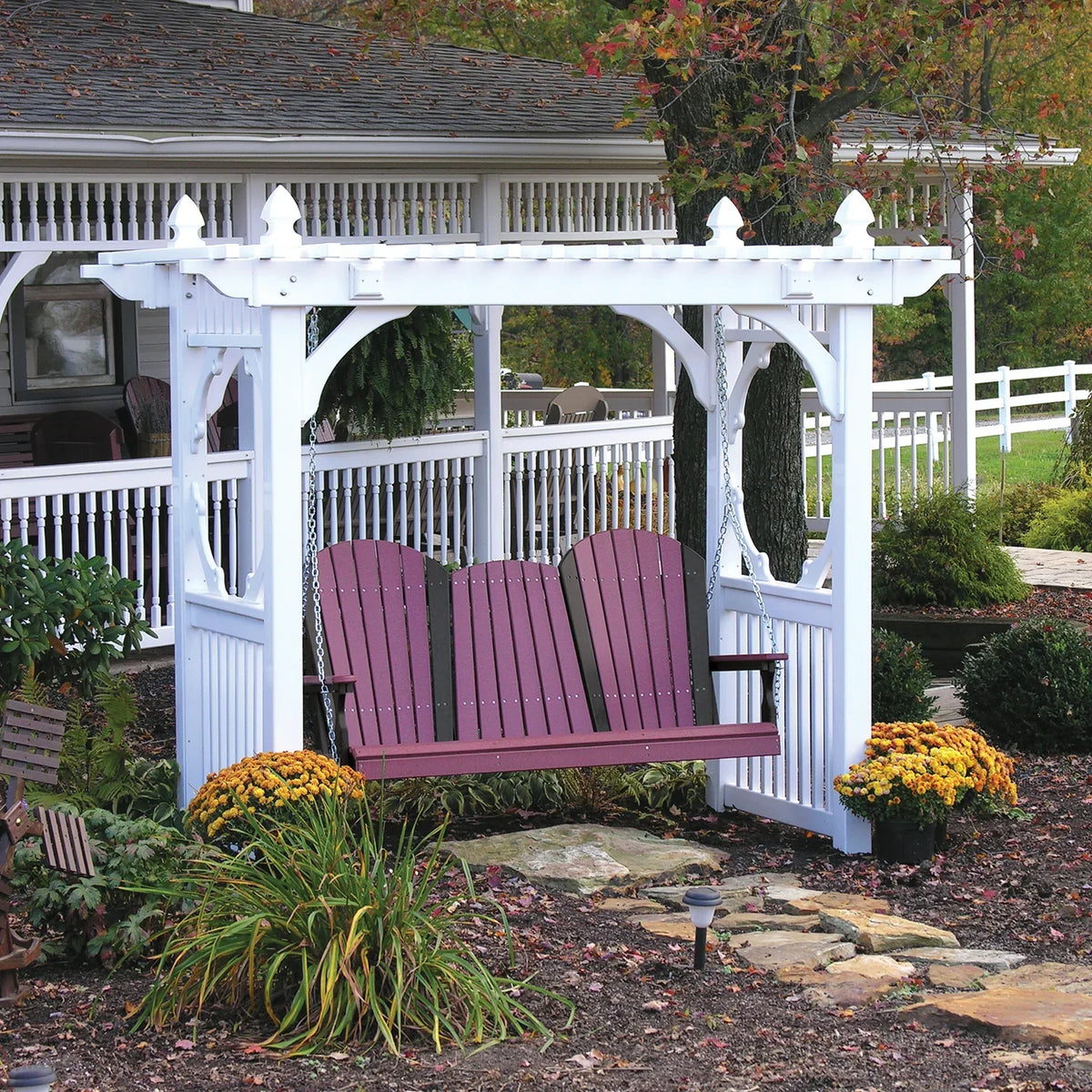 Vinyl swing stand featuring a white frame with intricate details, supporting a purple porch swing beside colorful flowers.