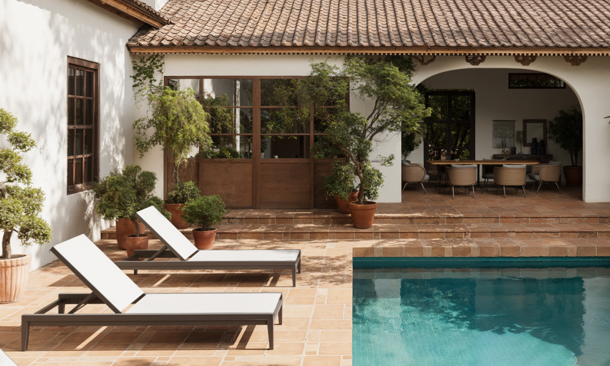 Charcoal aluminum chaise lounge with adjustable backrest and white sling fabric, positioned by a poolside patio.