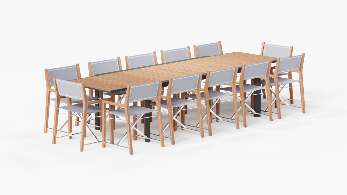 Extendable outdoor dining table with a teak top and aluminum frame, accompanied by 12 folding teak director's chairs with gray fabric.