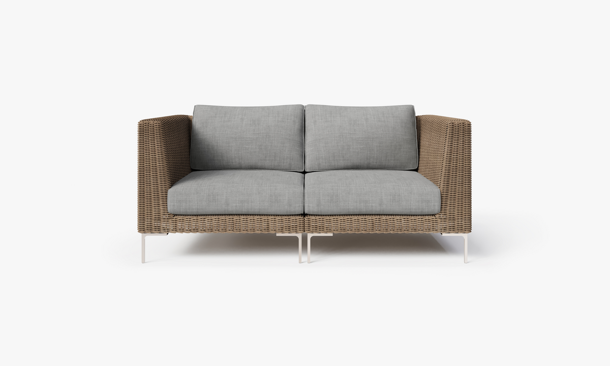 Handwoven brown wicker loveseat with grey cushions, featuring polished stainless steel legs for support.