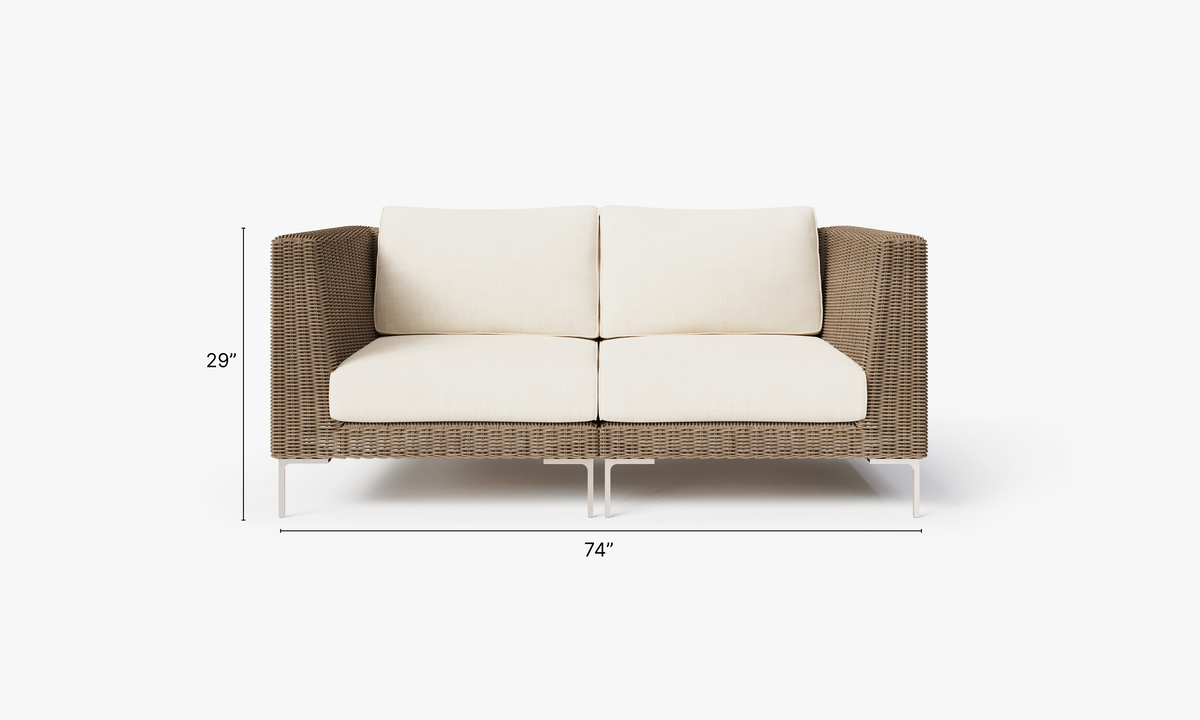 Handwoven brown wicker outdoor loveseat with cream cushions, polished stainless steel legs, and a modular design.
