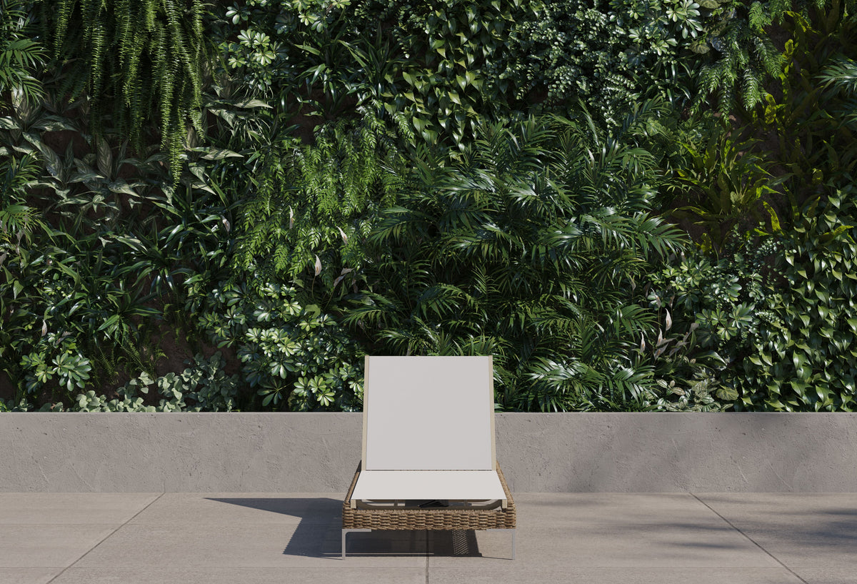 Brown wicker chaise lounge with adjustable backrest and sleek stainless steel legs, placed against a lush green wall.