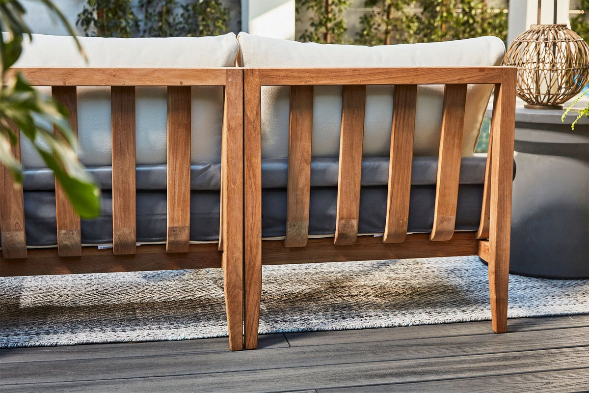 Teak U sectional outdoor sofa featuring a light cream cushion and a sturdy wooden frame with slatted backrest.