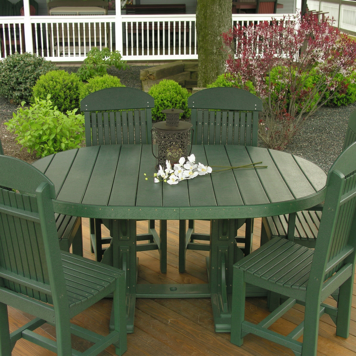 LuxCraft Deluxe Poly 4' x 6' oval table set in dark green, featuring spacious seating and a simple floral centerpiece.
