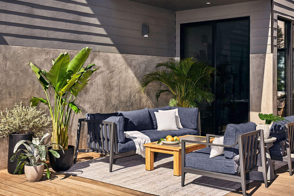 Charcoal aluminum U-shaped sectional with layered cushions, seating for seven, arranged on a wooden patio.