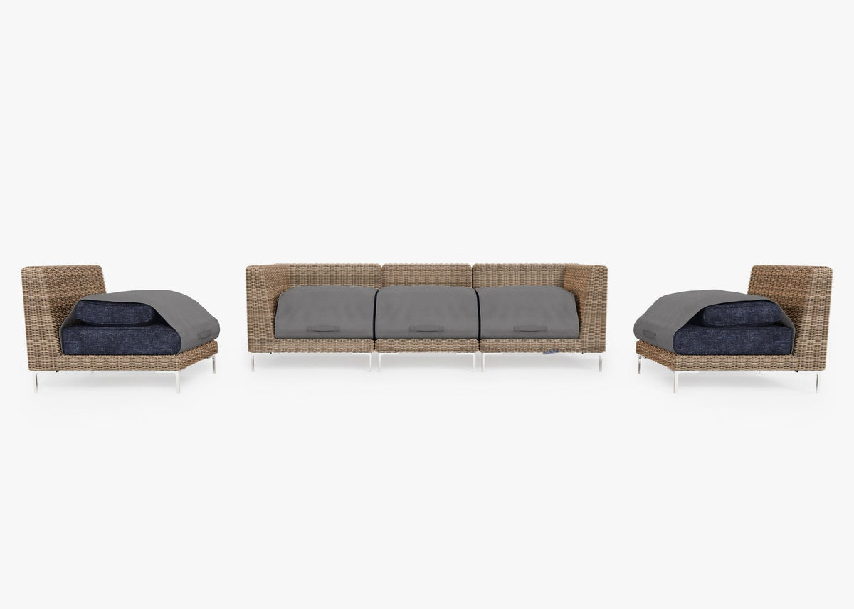 Handwoven brown wicker outdoor sofa set with three armless and two corner chairs; layered gray cushions are secured with covers.