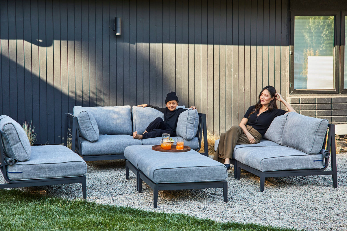 Charcoal aluminum outdoor sofa set with plush gray cushions, arranged with two armchairs and a central ottoman.