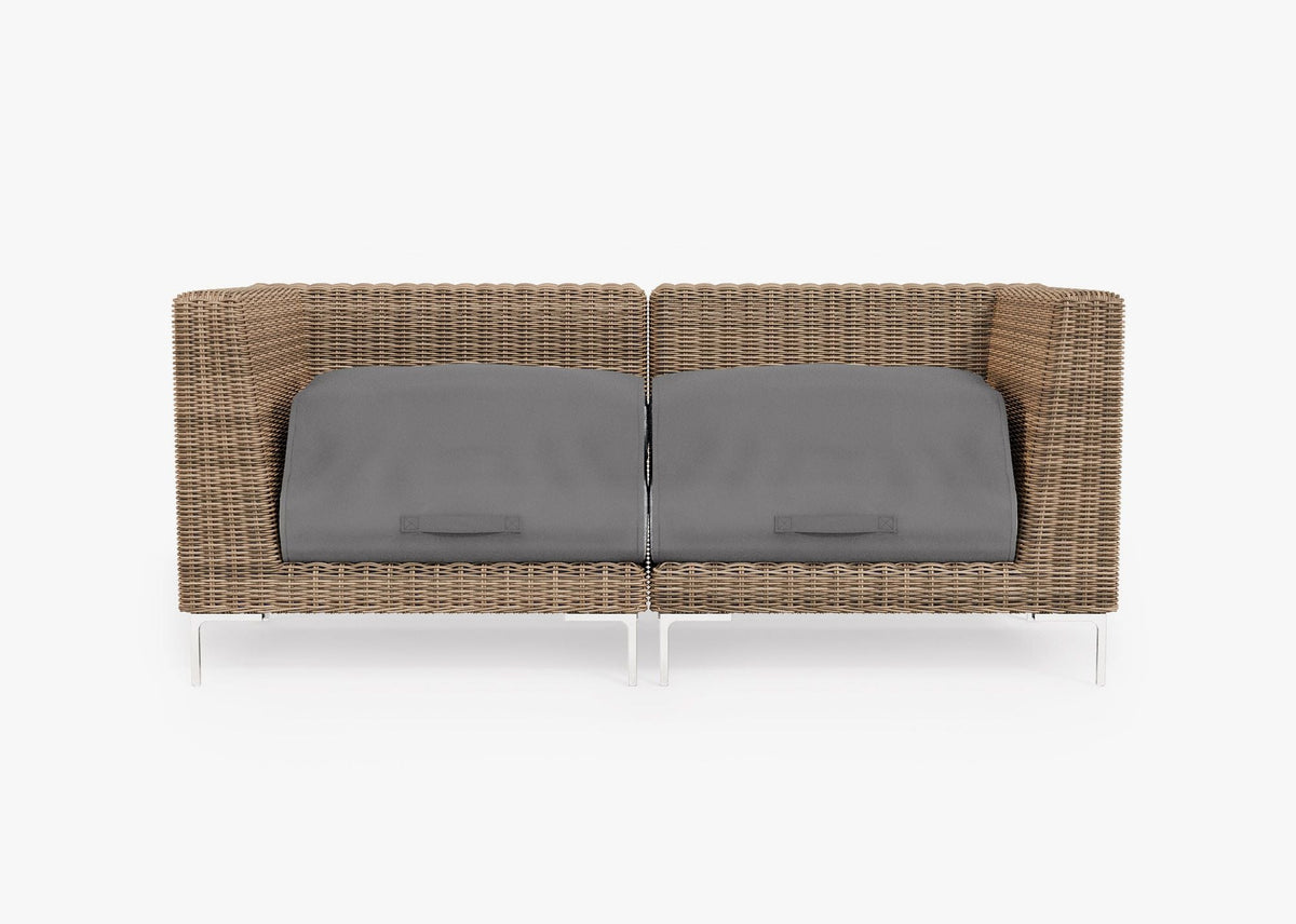 Handwoven brown wicker loveseat with gray cushion covers, featuring polished stainless steel legs in a modular design.
