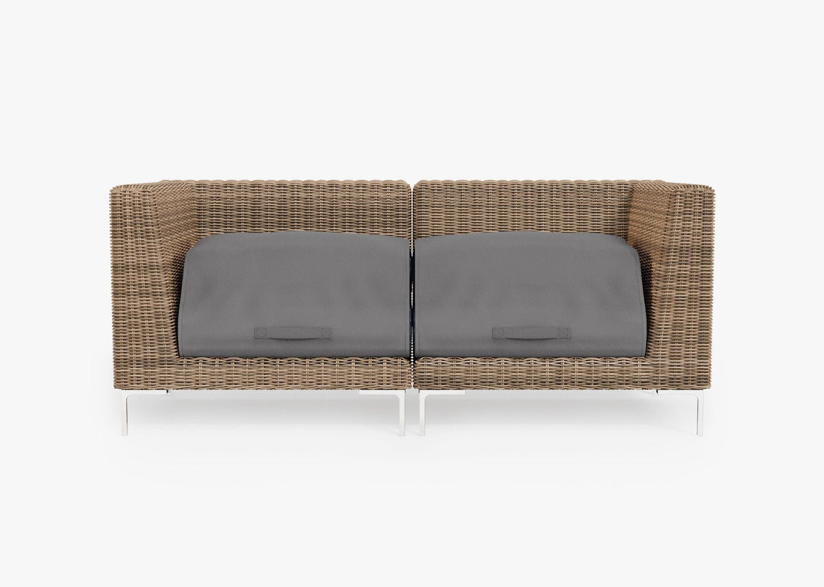 Handwoven brown wicker loveseat with polished stainless steel legs, featuring gray cushion covers for protection.