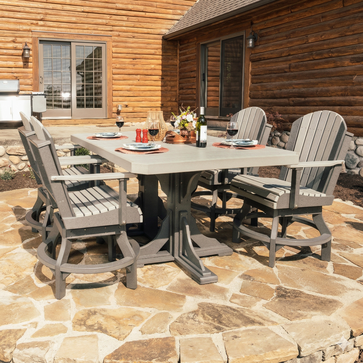 LuxCraft 4' x 6' rectangle table set in gray with six matching armchairs on a stone patio, set for outdoor dining.