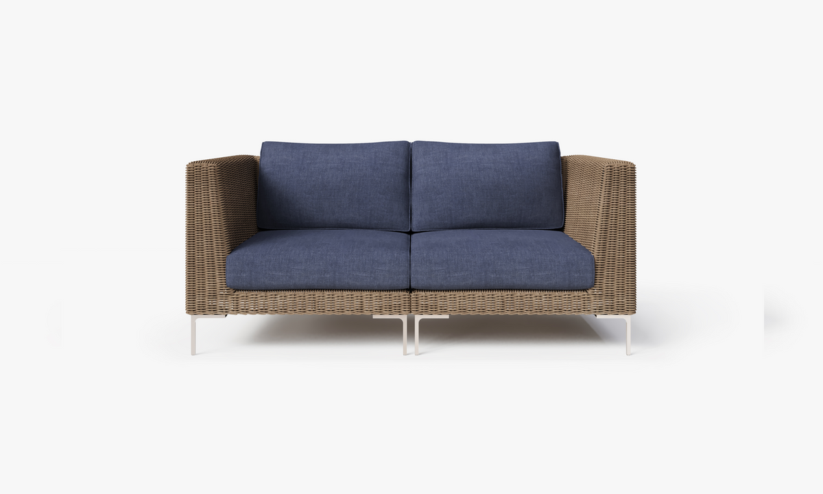 Handwoven brown wicker loveseat with deep blue cushions and polished stainless steel legs, showcasing a modern, comfortable design.