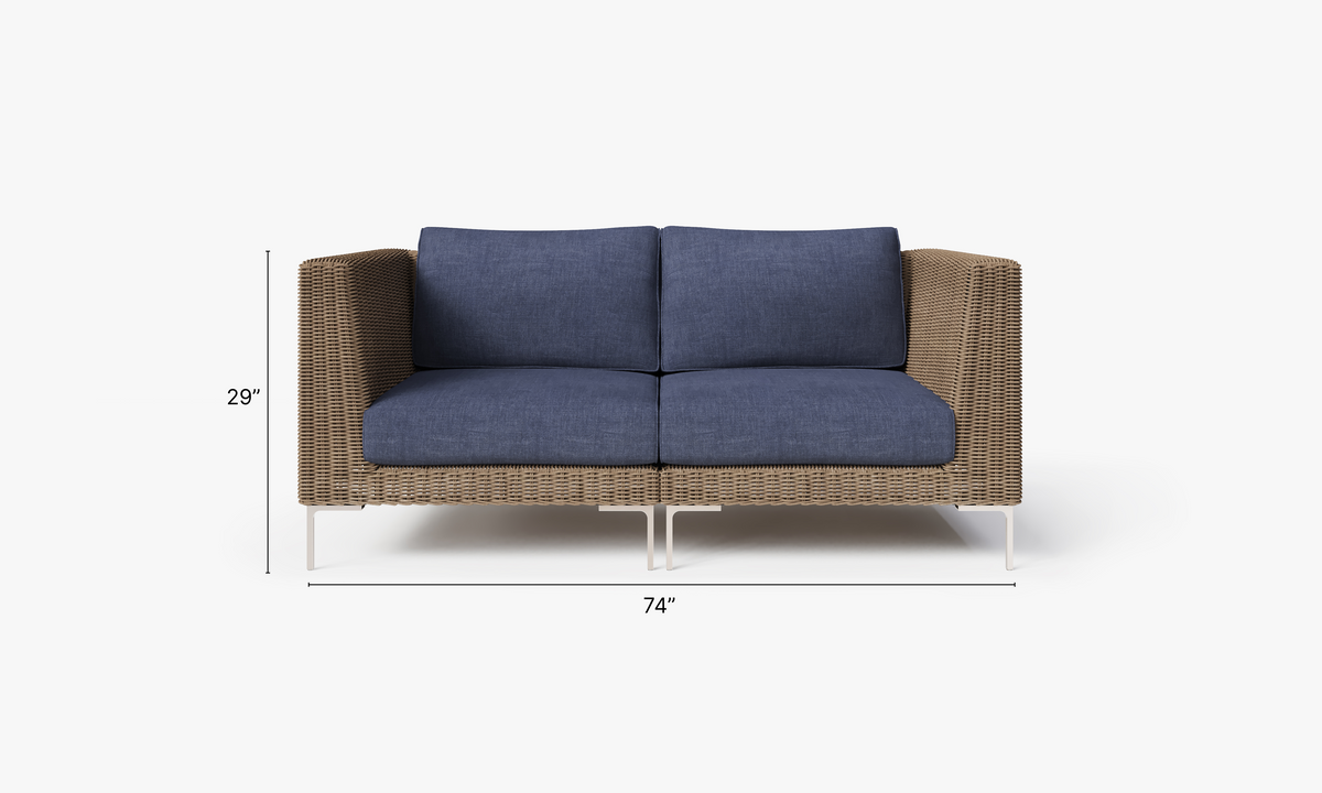 Handwoven brown wicker loveseat featuring deep blue cushions, polished stainless steel legs, and a modular design.