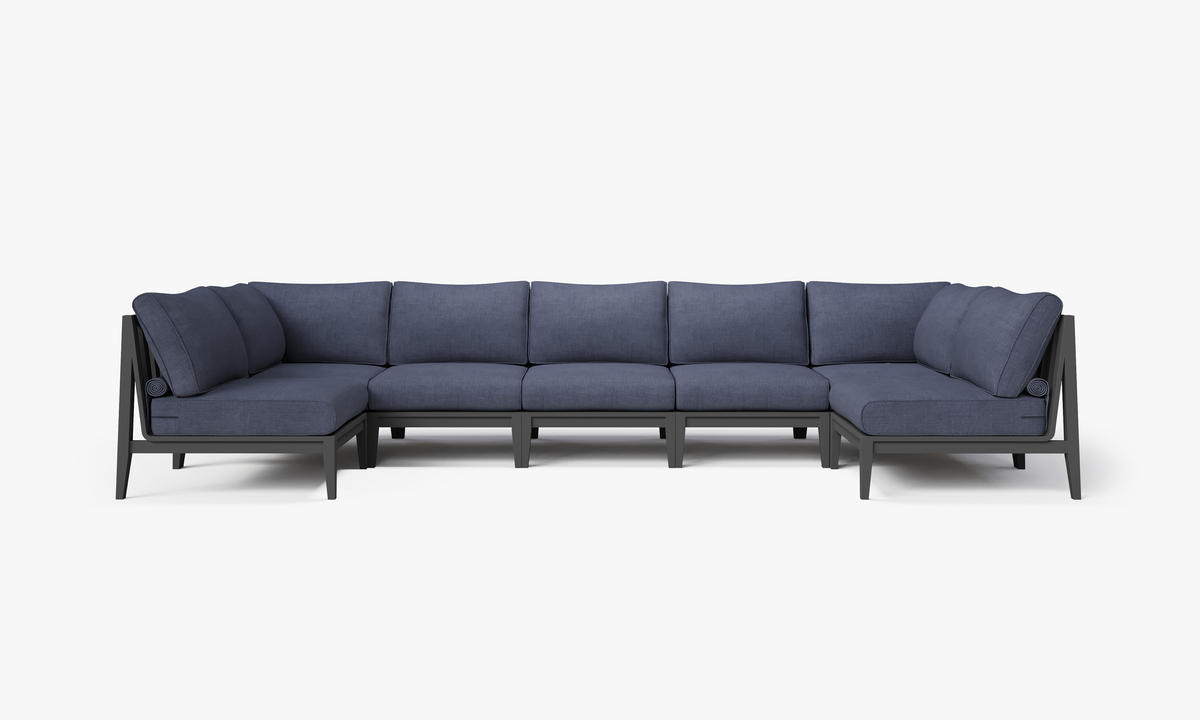 Charcoal aluminum U-shaped sectional sofa with layered navy cushions, designed for seven seats and modular arrangement.