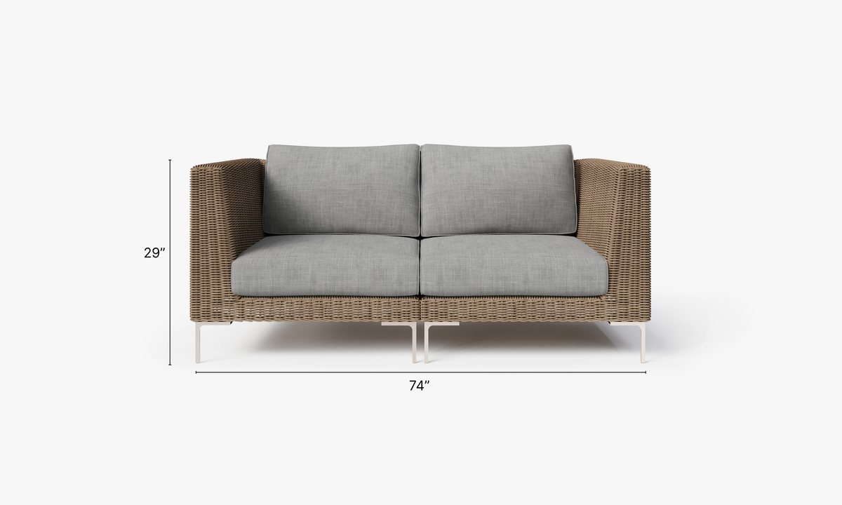 Handwoven brown wicker loveseat with gray cushions, featuring polished stainless steel legs and a modular design.