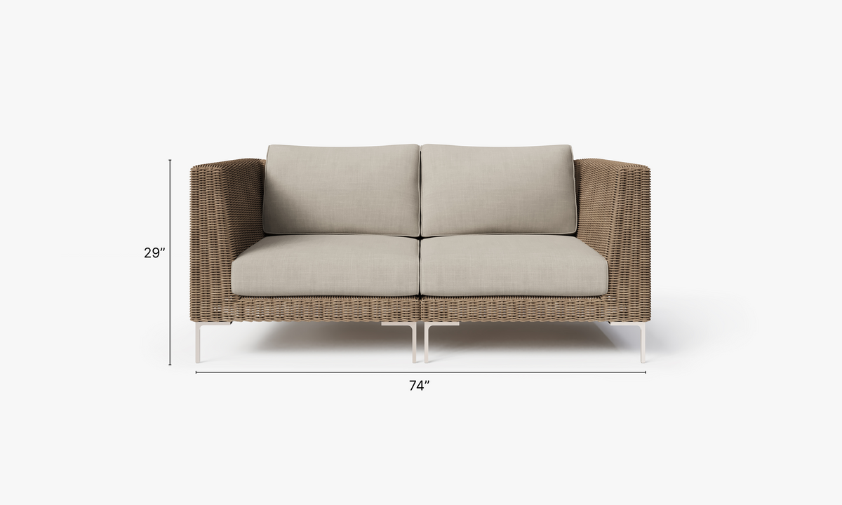 Brown handwoven wicker loveseat with plush beige cushions and polished stainless steel legs, modular design for flexible seating.