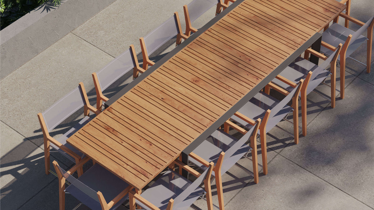 Extendable teak dining table with aluminum frame, accompanied by 12 folding director's chairs with gray sling fabric.