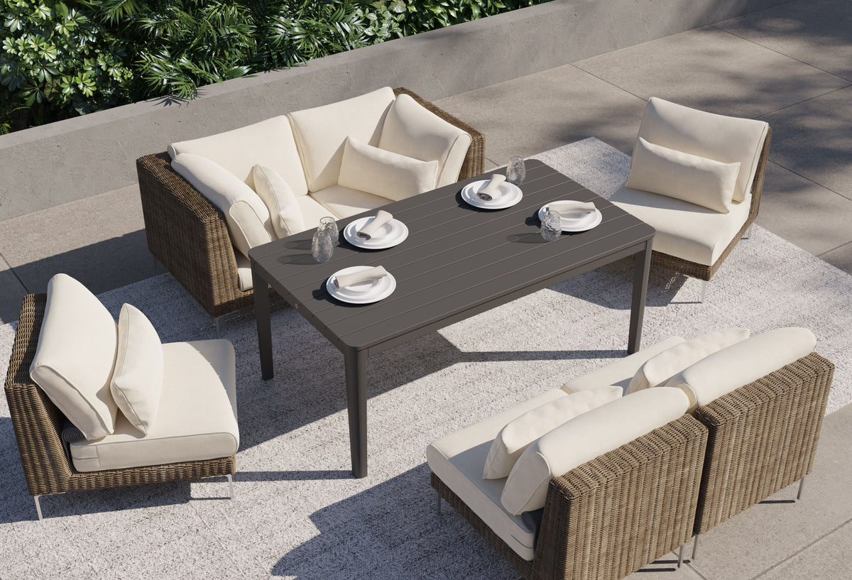 Brown handwoven wicker outdoor sofa set with cream cushions, including two armchairs and a corner chair, arranged around a table.