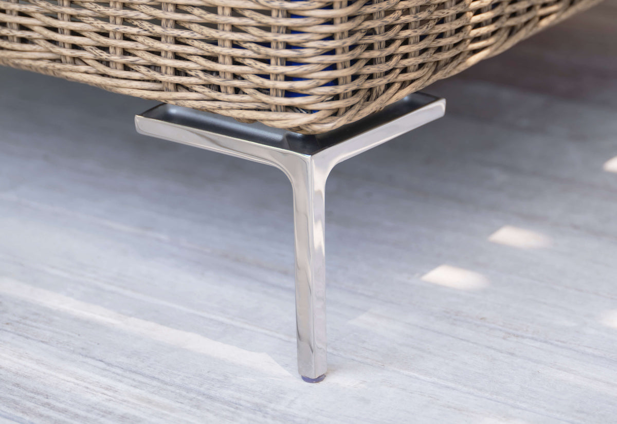 Brown handwoven wicker chair support with polished stainless steel legs, set against a light wooden surface.