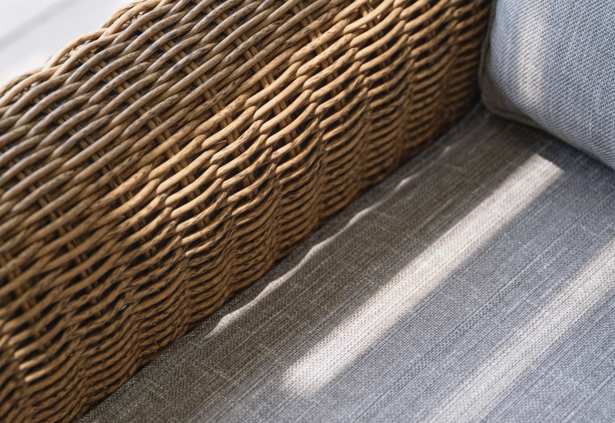 Handwoven brown wicker sofa featuring gray fabric cushions, showcasing texture and integrated cushion cover.