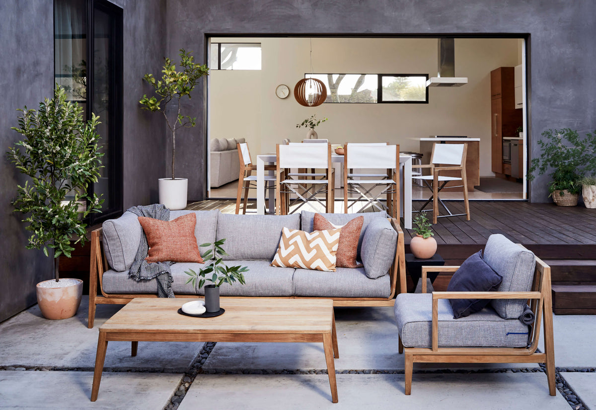 Teak outdoor U sectional, seven-seat configuration with gray cushions and wooden frame, featuring decorative pillows.