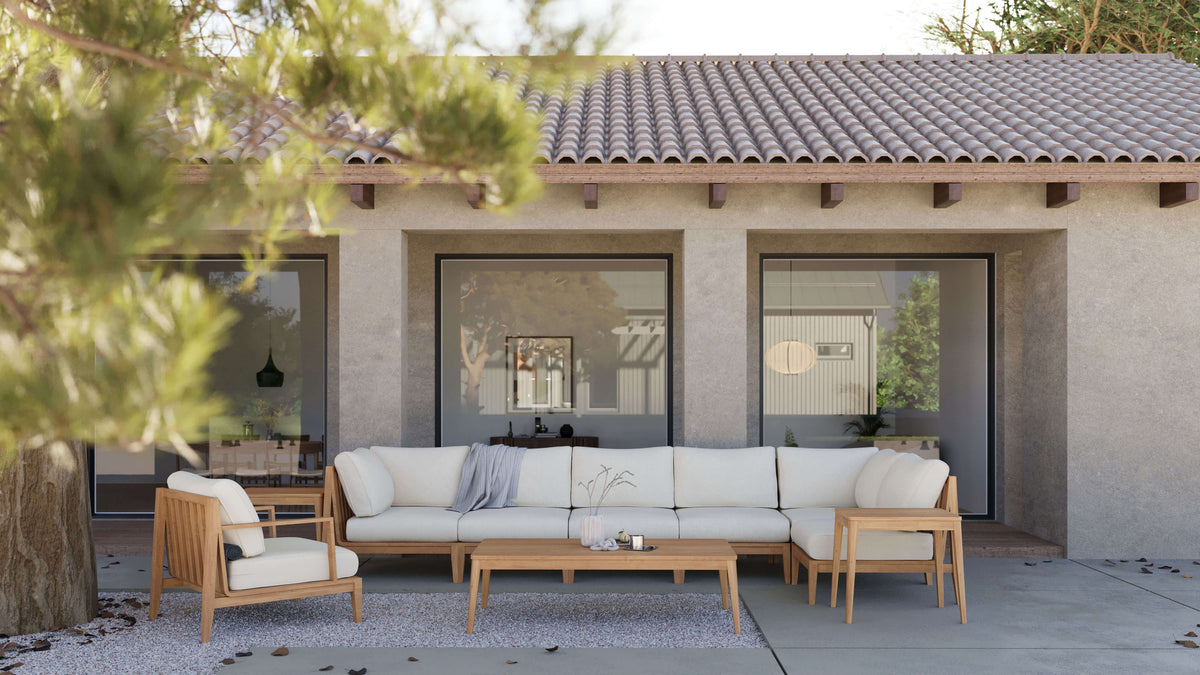 Three-seat outdoor sofa made of FSC-certified Grade A teak with cream-colored cushions, arranged in a cozy patio setting.
