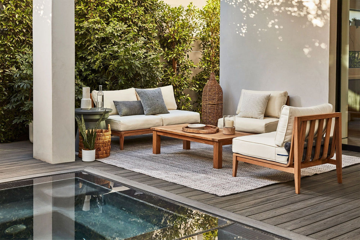 Three-seat outdoor sofa made of FSC-certified Grade A teak, featuring plush cream cushions and a modular design.